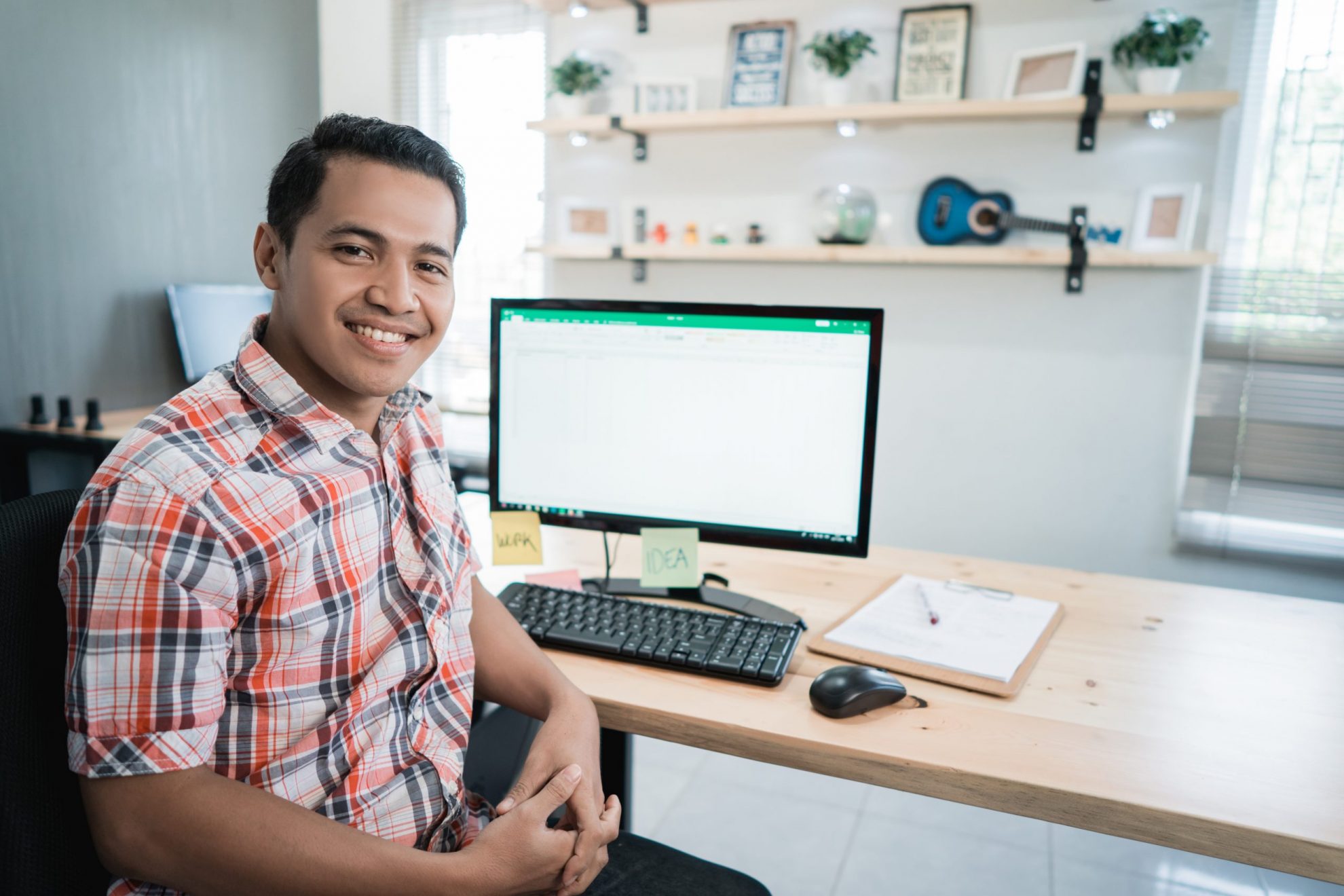 Photo of smiling man in front of computer illustrates blog: "How to Handle Past-Due Invoices"