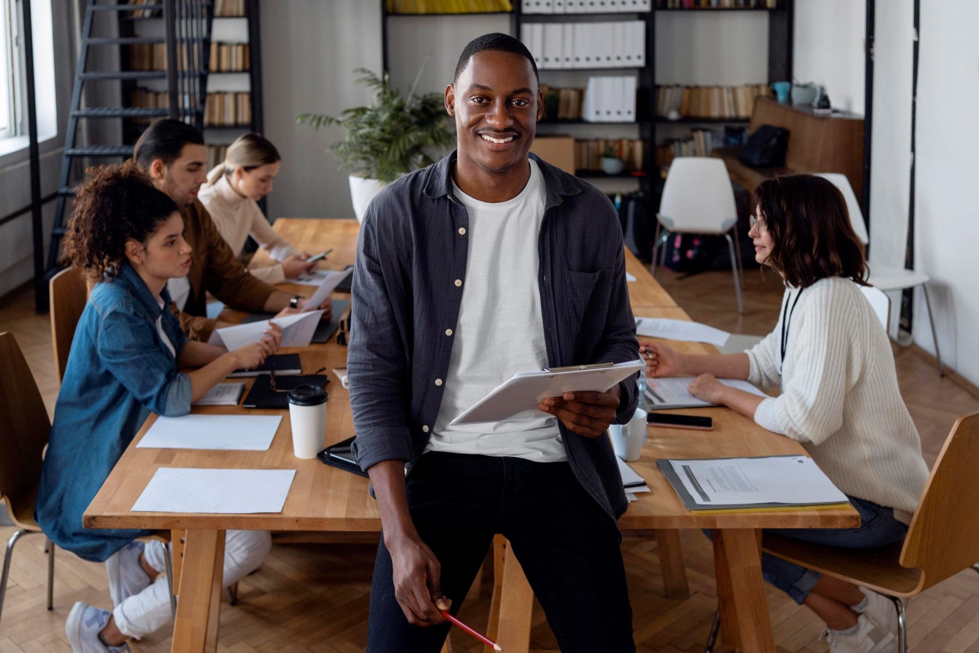 EntrepreneurYoung Smiling man in conference room illustrates blog "Invoice Factoring for Working Capital: Is It a Good Idea?"