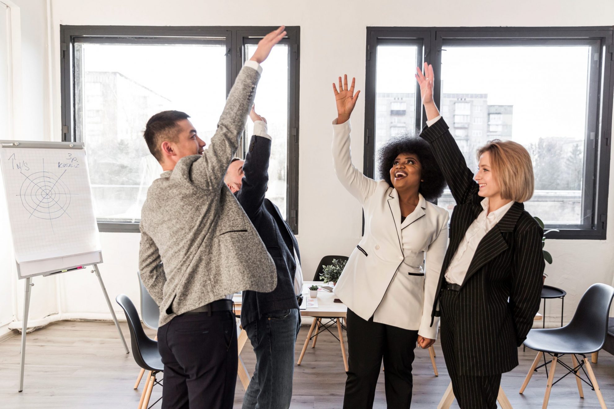 Group of four people high-fiving each other illustrates blog "4 Ways to Fund Business Growth"