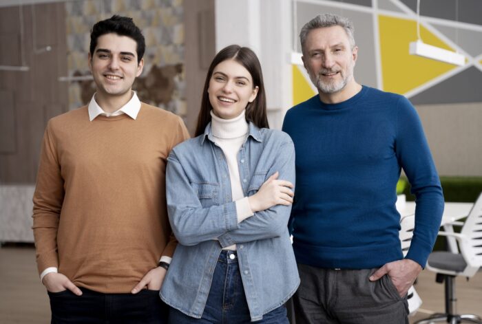 Two men and a woman smiling and dressed casually illustrate blog "What Is a Factoring Company? "