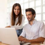 Man and woman looking at laptop illustrates blog "Are Cash Flow and EBITDA the Same?"