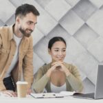 Man and woman looking at laptop illustrate blog "What Are the Benefits of Receivables Management?"
