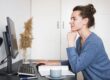 Woman sitting at desk looking at computer illustrates blog "Do Factoring Companies Check Your Credit?"