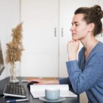 Woman sitting at desk looking at computer illustrates blog "Do Factoring Companies Check Your Credit?"