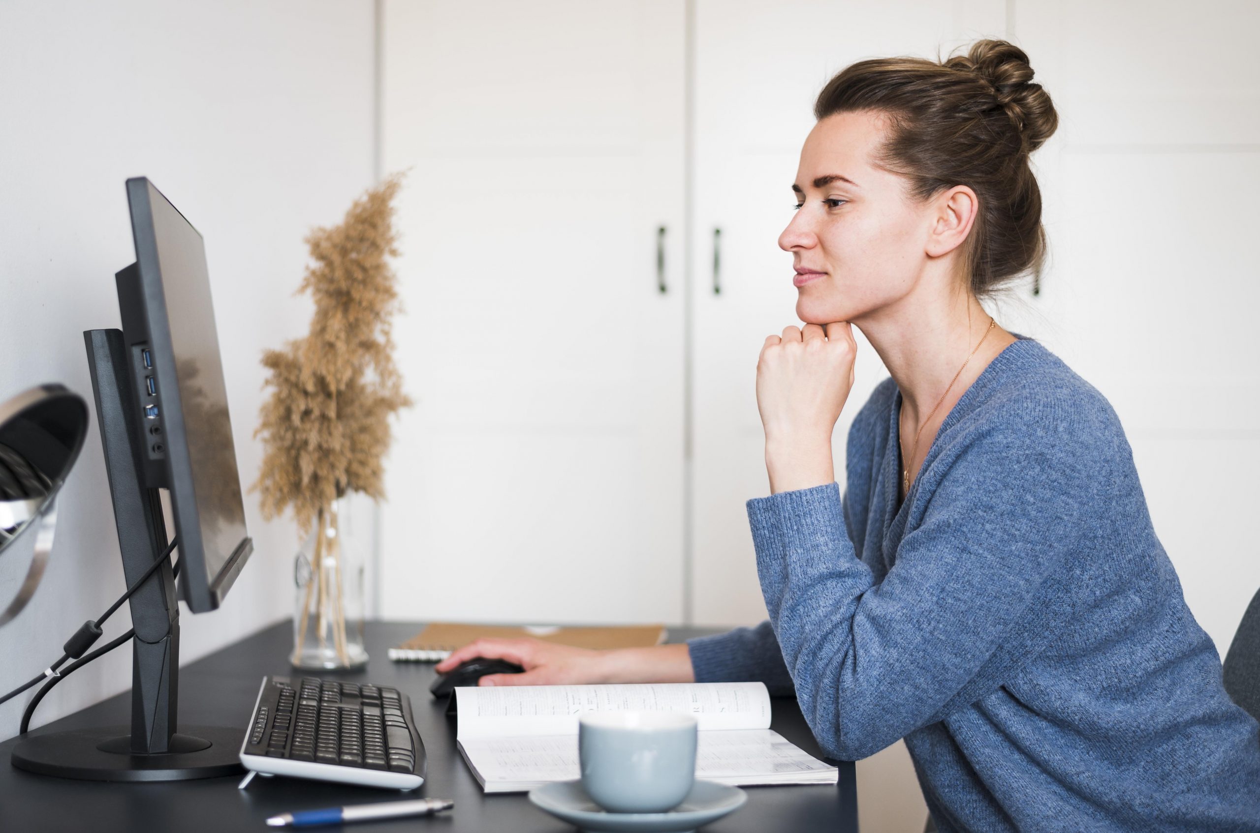 Woman sitting at desk looking at computer illustrates blog "Do Factoring Companies Check Your Credit?"