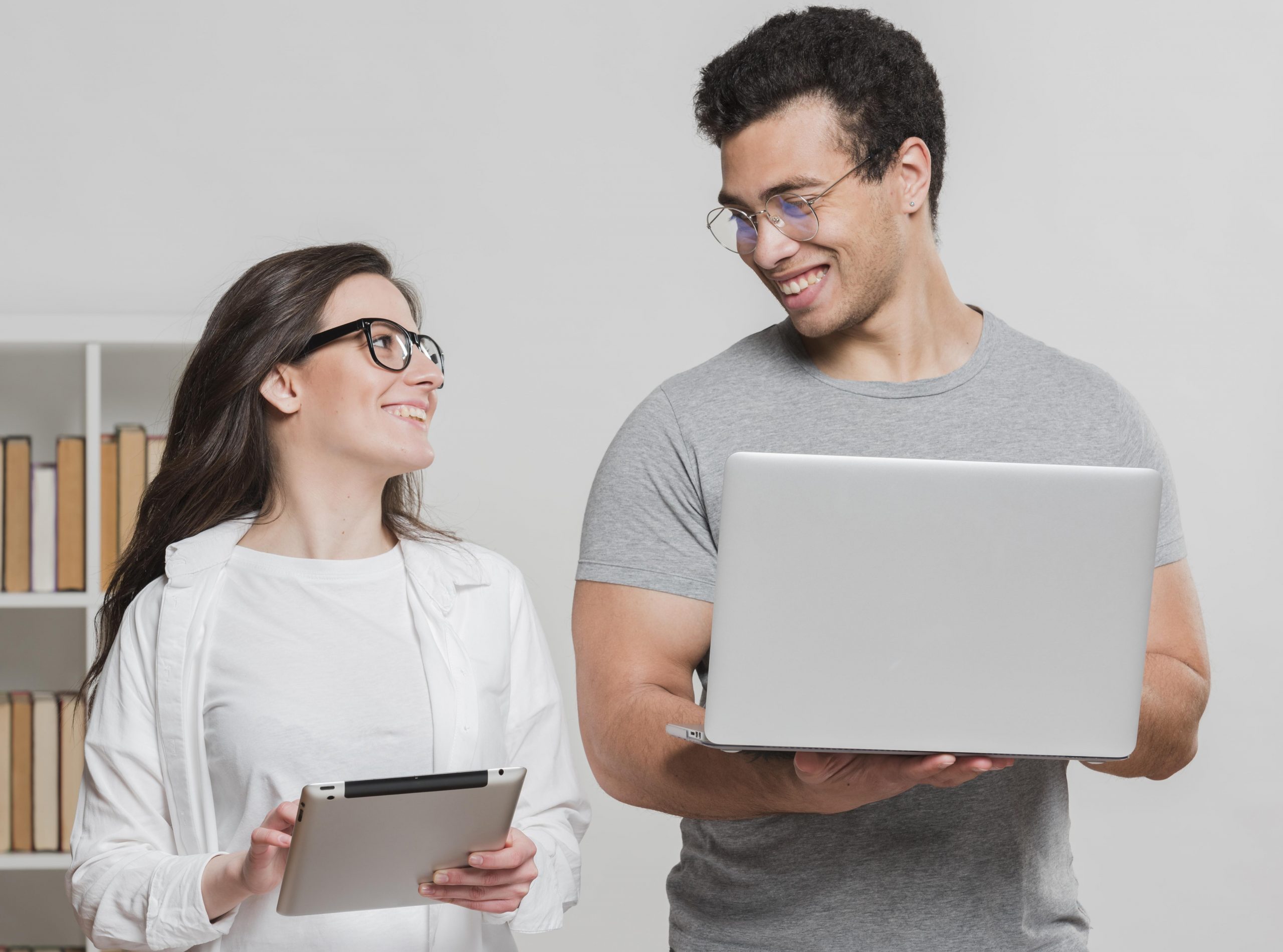 Woman and man holding laptops and looking at each other illustrate blog "You’ve probably heard the term “no-doc” business loan thrown around a lot these days. And even if you don’t know what a no-doc loan is exactly, you probably understand that it’s less complicated than a traditional loan. But does factoring fall within this category? Keep reading to find out."