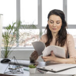 realistic small business owner reviewing invoices and cash flow documents with a financing advisor in an office