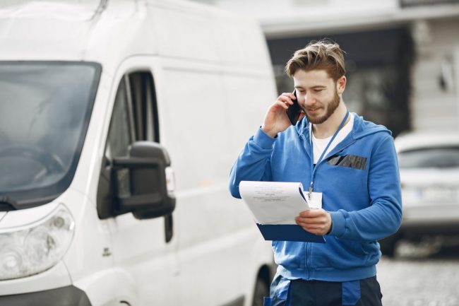 Photo of man standing beside delivery van illustrates blog :Why Use Invoice Factoring?"