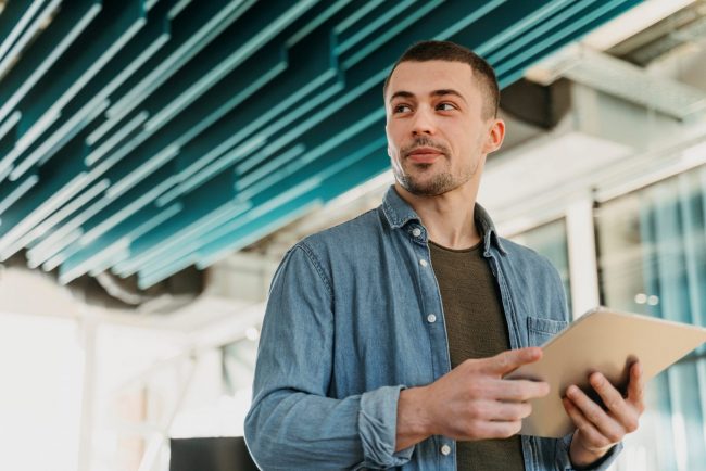 Photo of man holding clipboard illustrates blog: "3 Reasons to Choose Factoring Over Bank Loans"