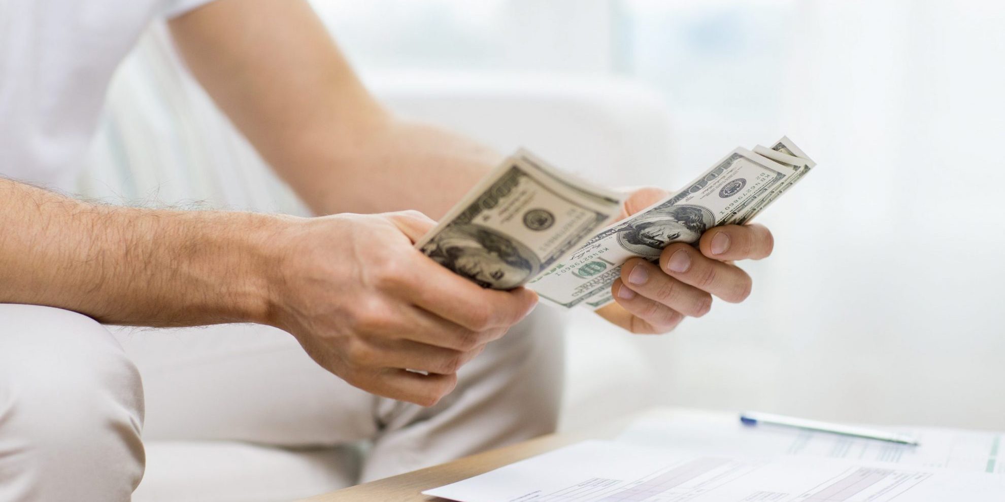 Photo of man counting dollars illustrates blog: "Accounts Receivable vs Cash: What Is the Difference? Which One Is Best?"s