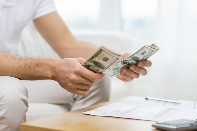 Photo of man counting dollars illustrates blog: "Accounts Receivable vs Cash: What Is the Difference? Which One Is Best?"s