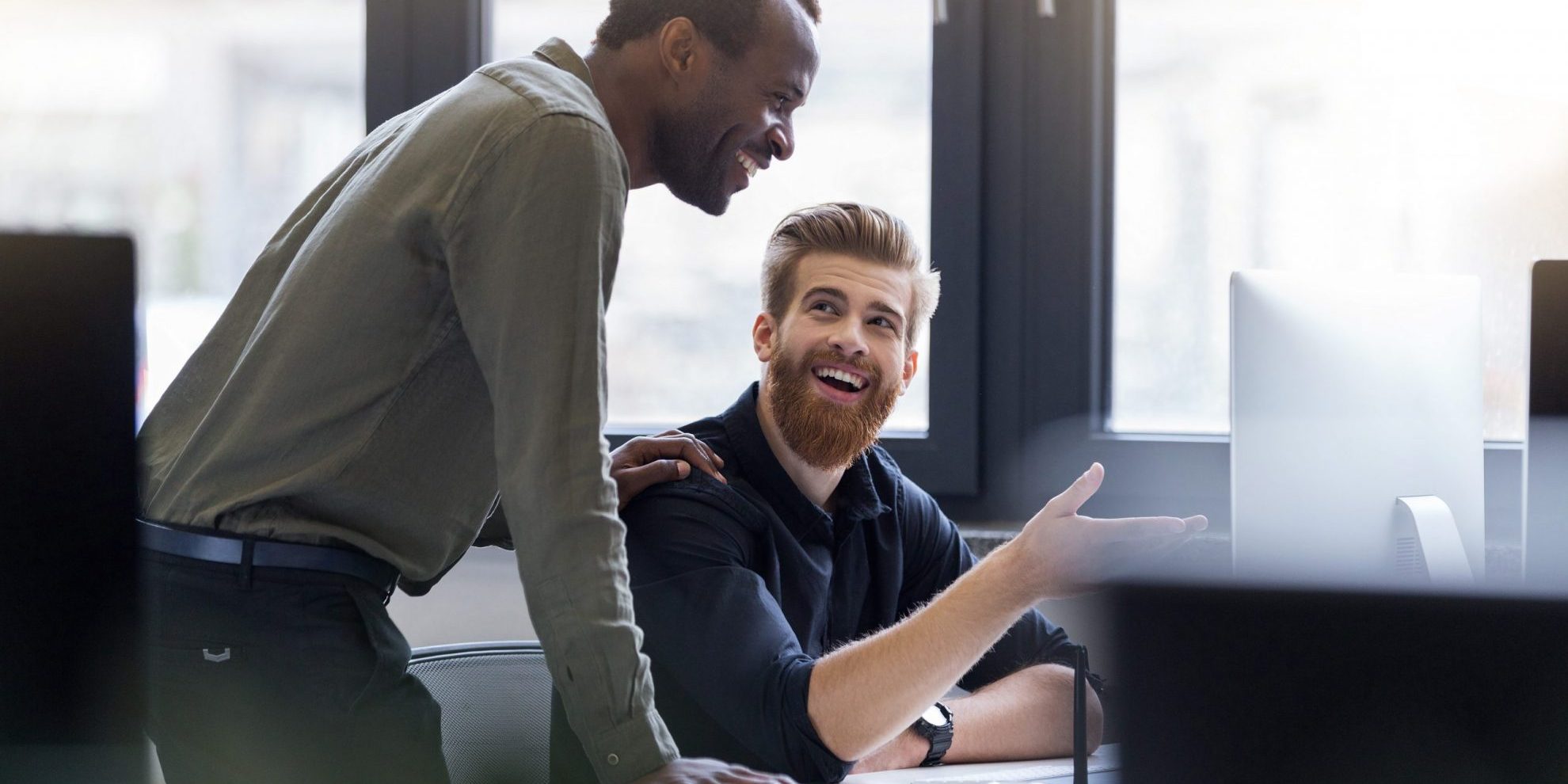 Photo of two smiling men at work illustrates blog: "How Do You Qualify for Receivables Factoring?"