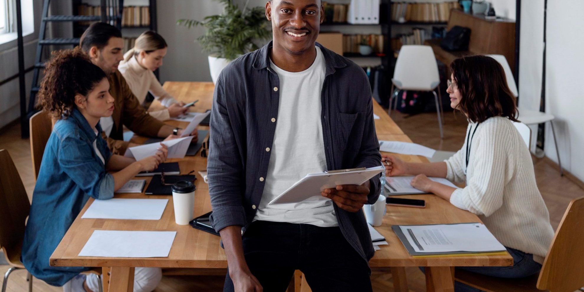 EntrepreneurYoung Smiling man in conference room illustrates blog "Invoice Factoring for Working Capital: Is It a Good Idea?"
