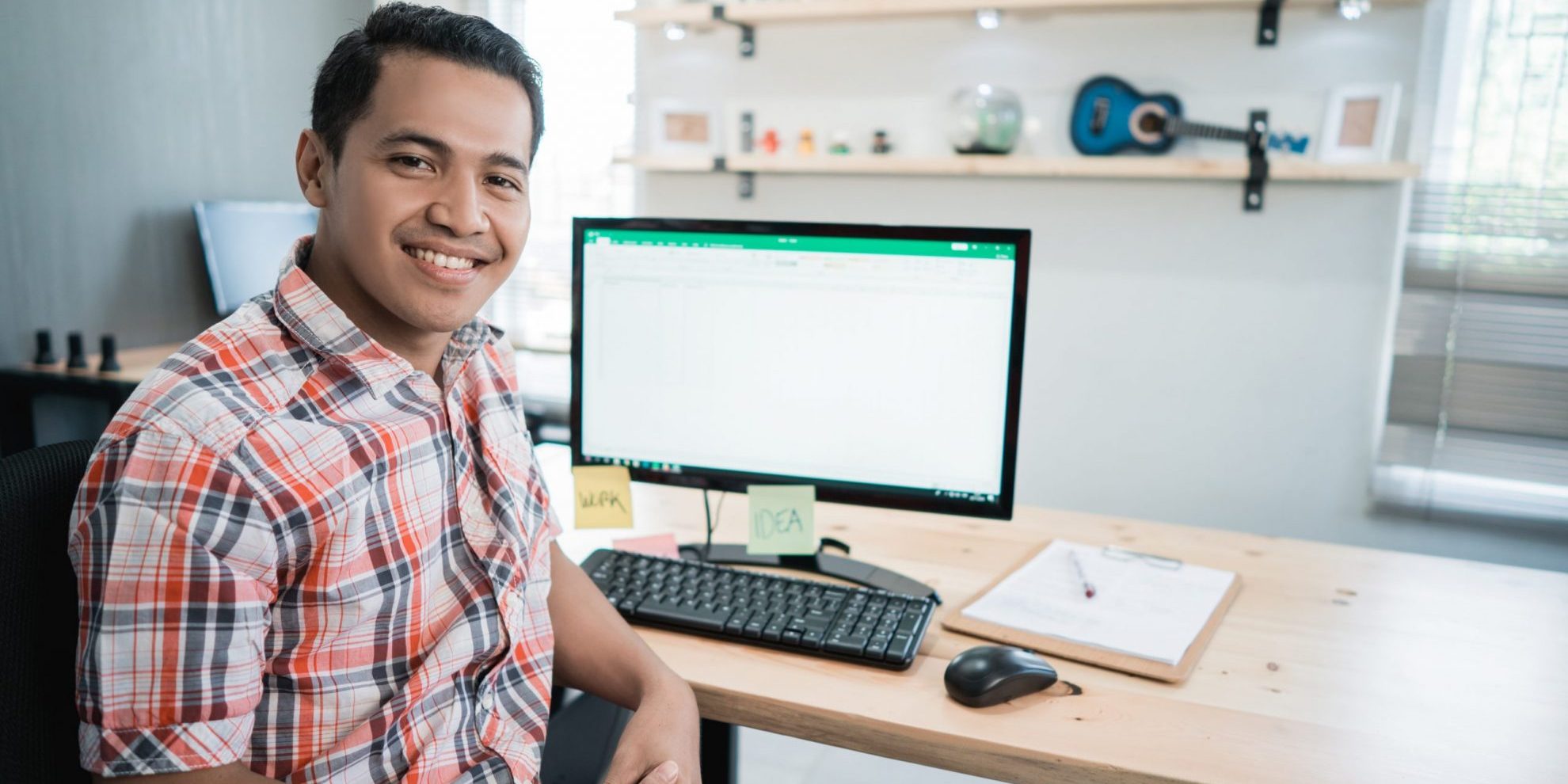 Photo of smiling man in front of computer illustrates blog: "How to Handle Past-Due Invoices"