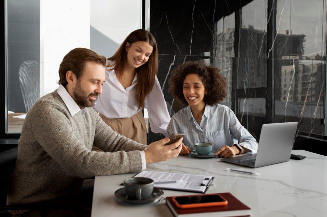 bad-debt-FP Office workers looking at smartphone illustrate blog "4 Tips To Avoid Bad Debt"