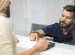 Bank customer talking to teller illustrate blog "Bank Loans Are Getting Harder To Obtain: Here’s Why (and What To Do About It)"
