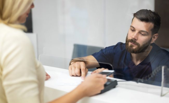 Bank customer talking to teller illustrate blog "Bank Loans Are Getting Harder To Obtain: Here’s Why (and What To Do About It)"