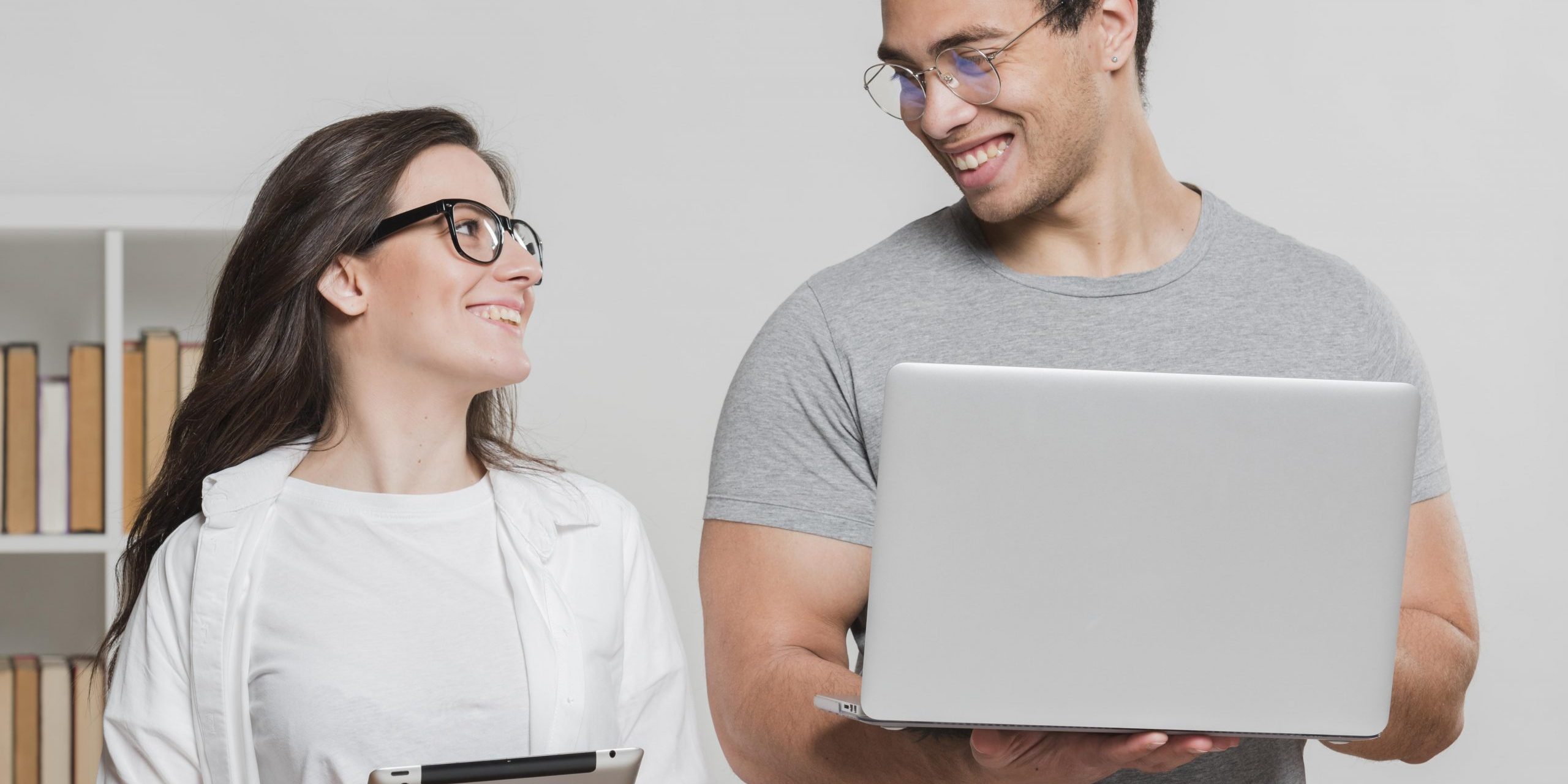 Woman and man holding laptops and looking at each other illustrate blog "You’ve probably heard the term “no-doc” business loan thrown around a lot these days. And even if you don’t know what a no-doc loan is exactly, you probably understand that it’s less complicated than a traditional loan. But does factoring fall within this category? Keep reading to find out."