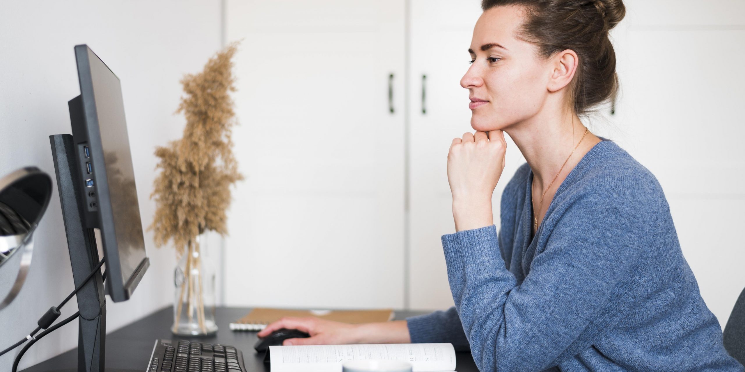 Woman sitting at desk looking at computer illustrates blog "Do Factoring Companies Check Your Credit?"